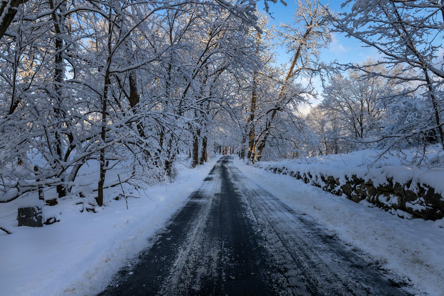 Scenic winter road through snow-covered forest in Southborough, MA. Serene and picturesque landscape.
